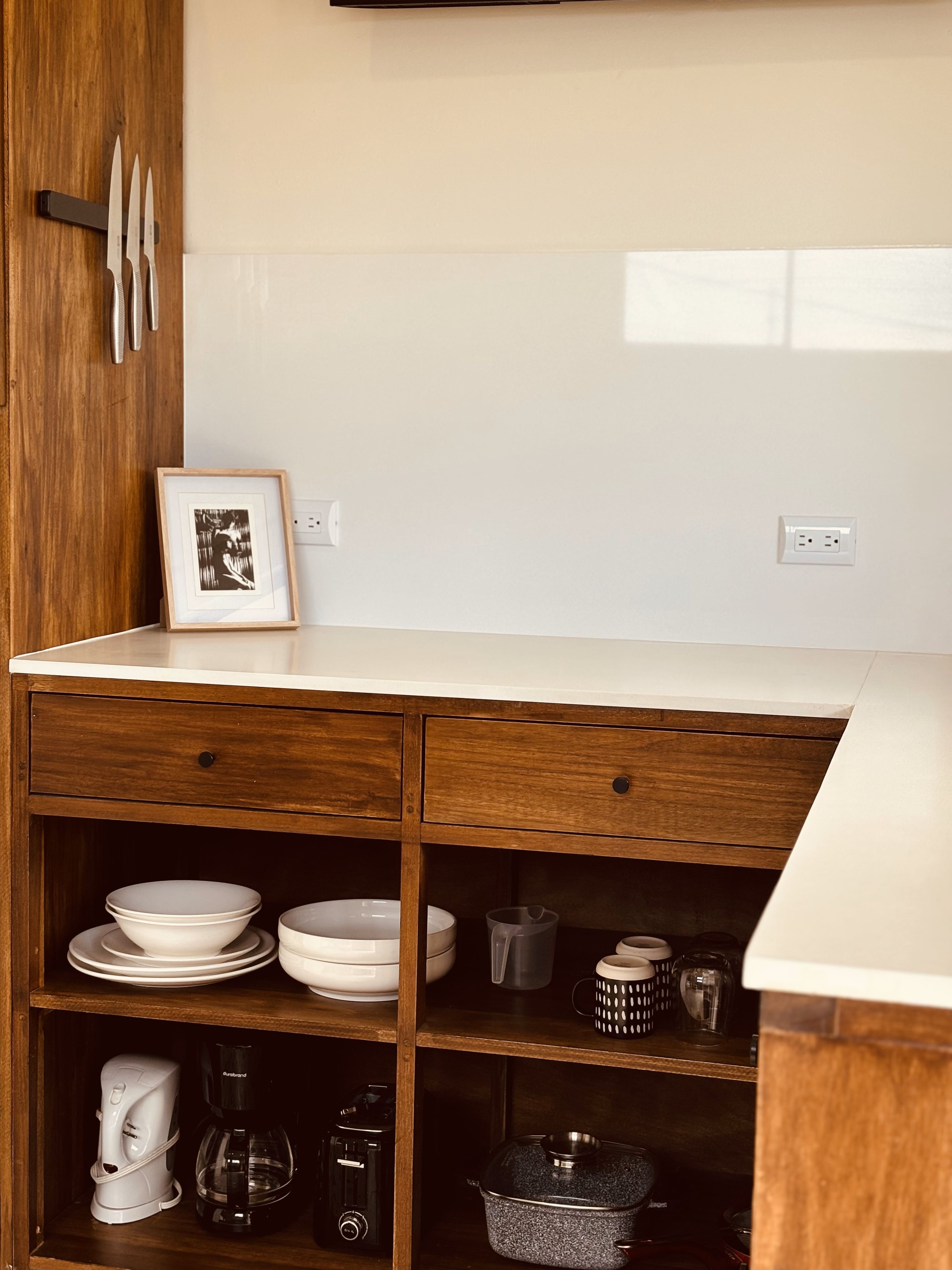 A kitchen with wooden cabinets, a white countertop, and various kitchenware.