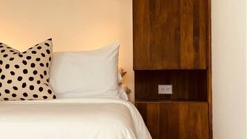 Un dormitorio con una cama, un armario de madera y una lámpara fijada a la pared.