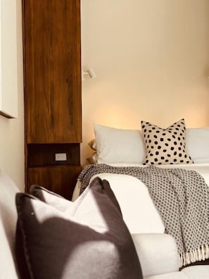A bedroom with a bed, pillows, a nightstand, and a wooden wardrobe.