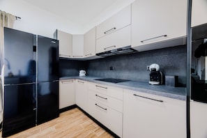 A modern kitchen with a black refrigerator, white cabinets, a black coffee maker, and a black range hood. - A1 - luxury apartment near beach with big terrace and the sea view (Kaštel Gomilica)