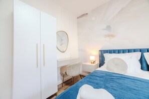 A hotel room with a bed, a white wardrobe, a round mirror, a small white chair, and a nightstand with a lamp. - A1 - luxury apartment near beach with big terrace and the sea view (Kaštel Gomilica)