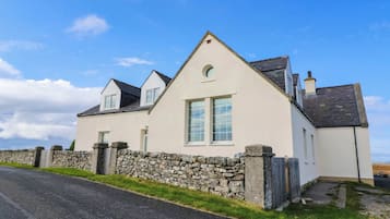 Ein zweistöckiges Haus mit einer Steinmauer, einem Satteldach und einem kleinen Fenster.