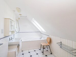 Un baño moderno con bañera, lavamanos, una silla y ducha.