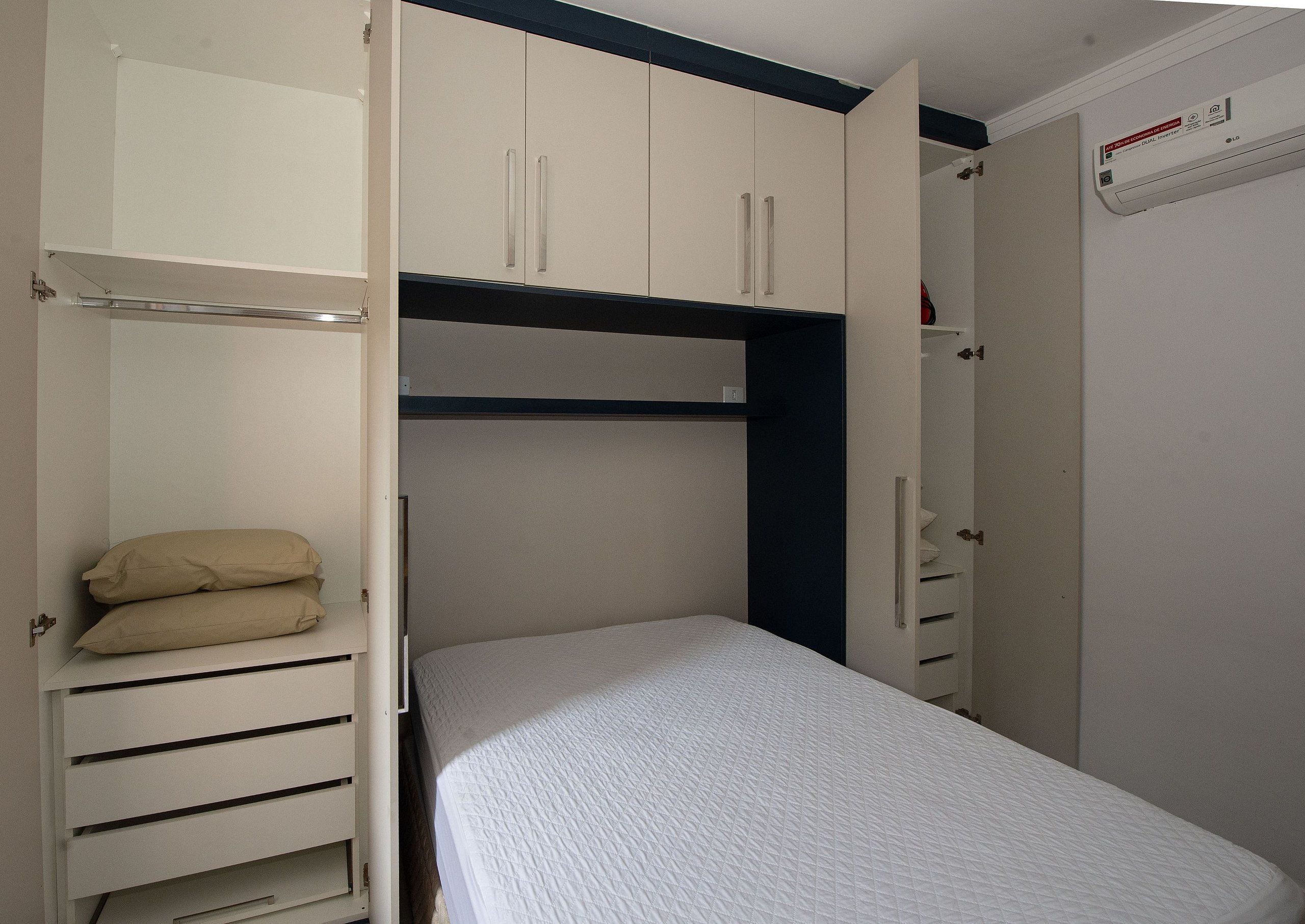 A room with a bunk bed, a wardrobe with multiple compartments, and a heater on the wall.