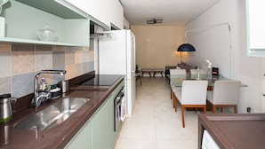 A modern kitchen with a sink, stove, and refrigerator, leading to a dining area with a table and chairs.