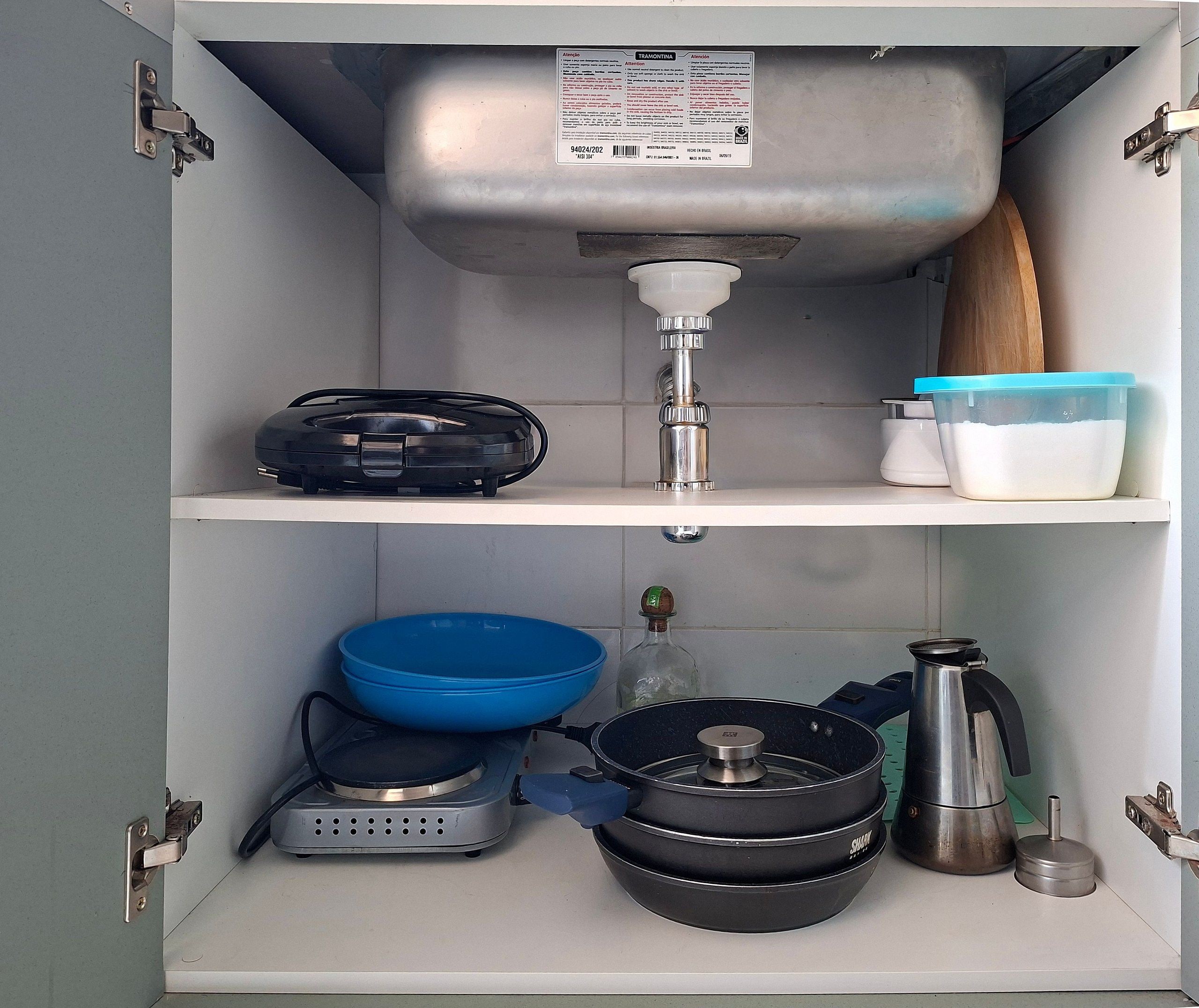 A kitchen with a sink, a coffee maker, a blender, a kettle, and a blue bowl.