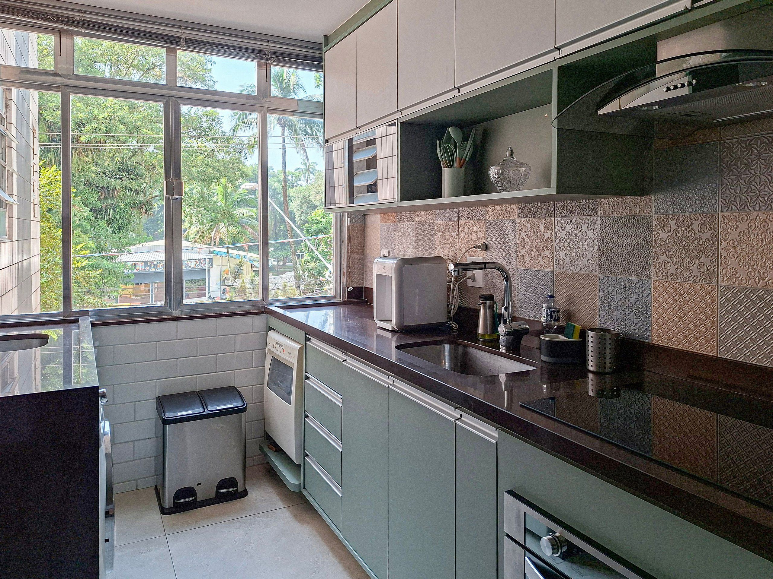 Une cuisine moderne dotée d’une fenêtre, d’appareils électroménagers en acier inoxydable et d’un revêtement mural décoratif.