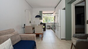A compact living space with a kitchenette, a sofa, a dining table, and a chair.