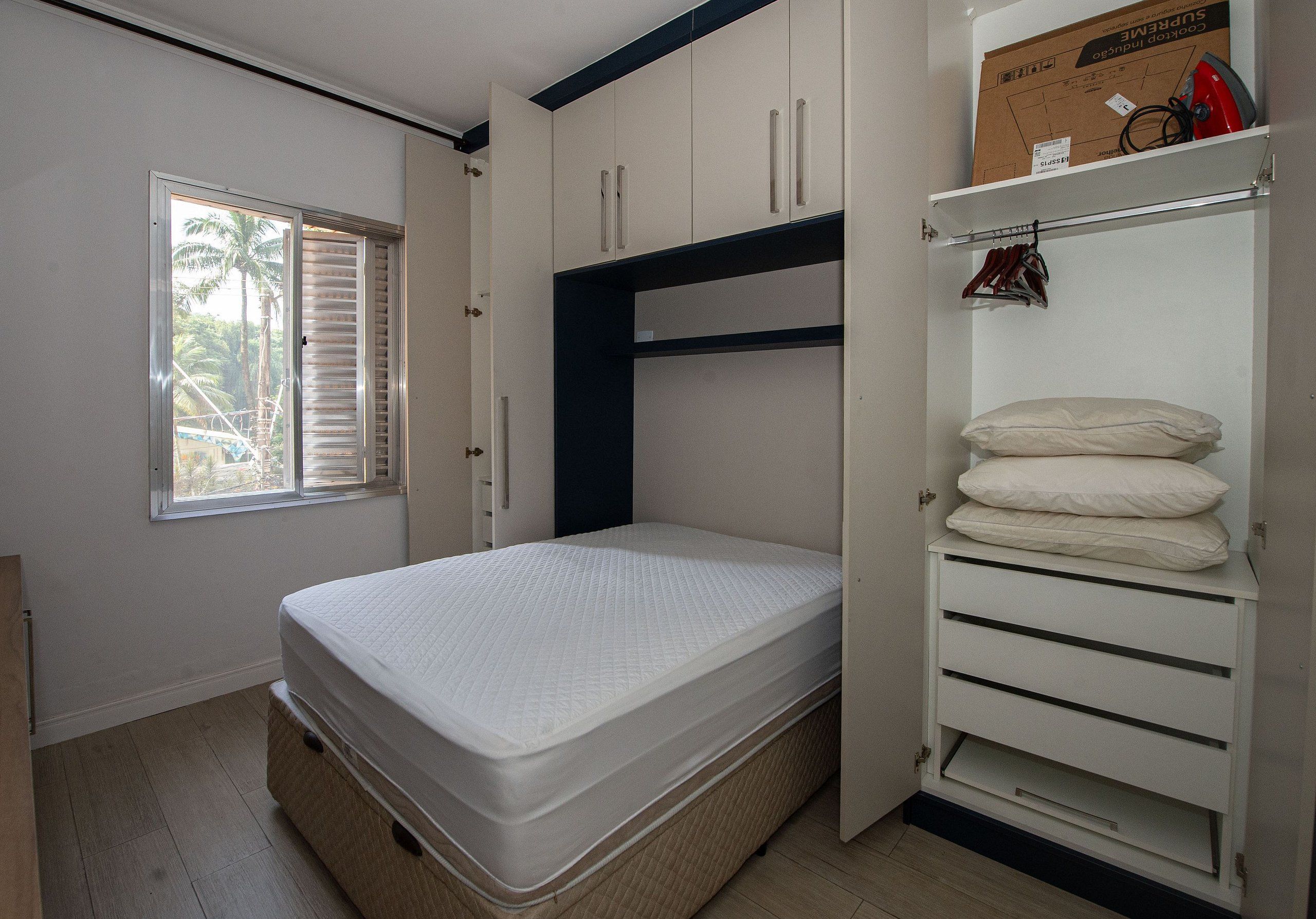 Une chambre à coucher avec un lit, une armoire intégrée et une fenêtre avec des stores.
