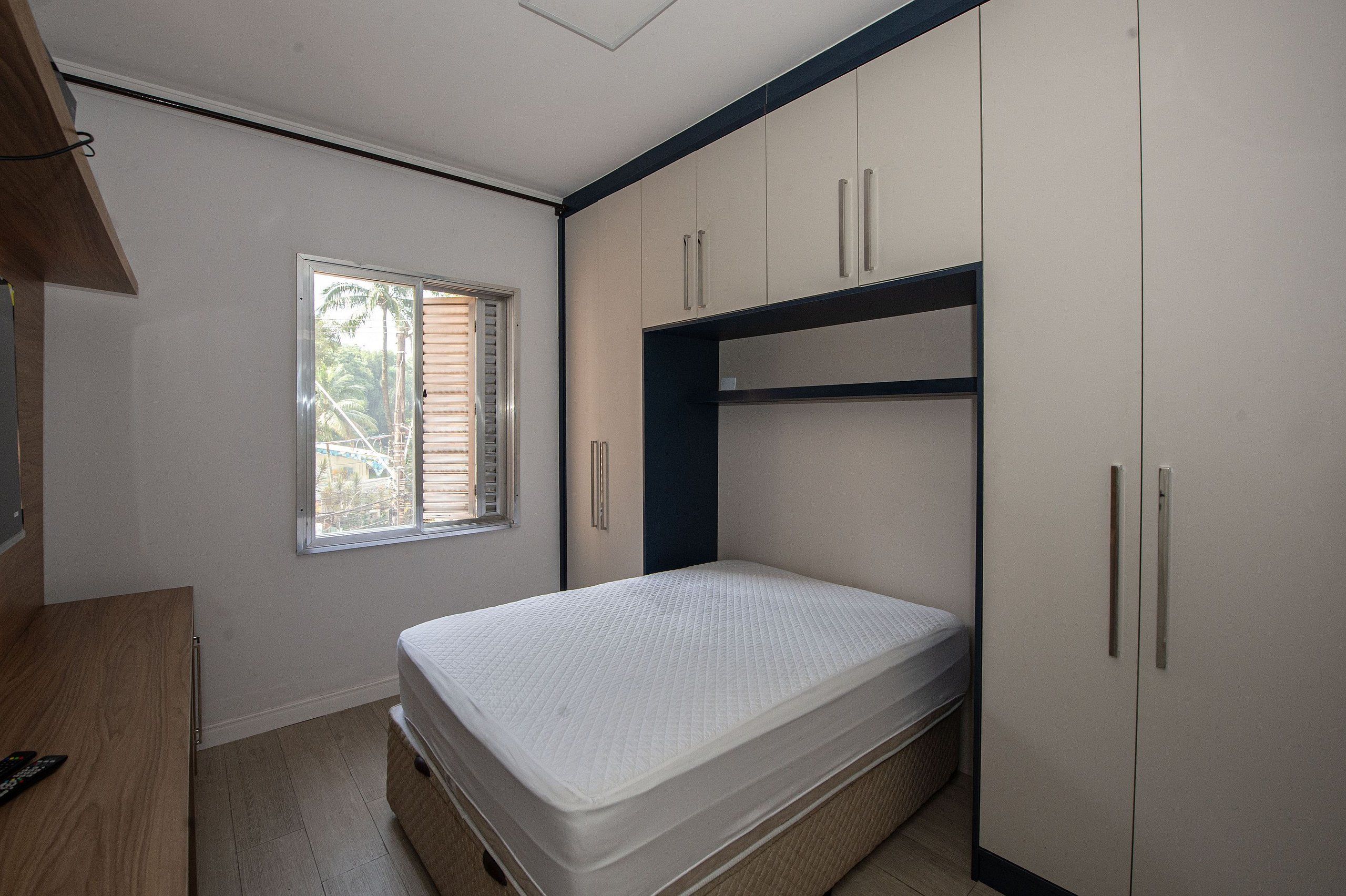 A bedroom with a bed, a window, and built-in wardrobes.