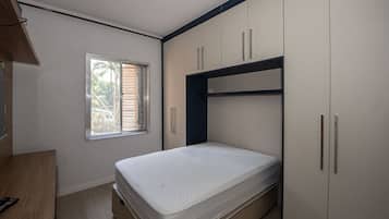 A bedroom with a bed, a window, and built-in wardrobes.