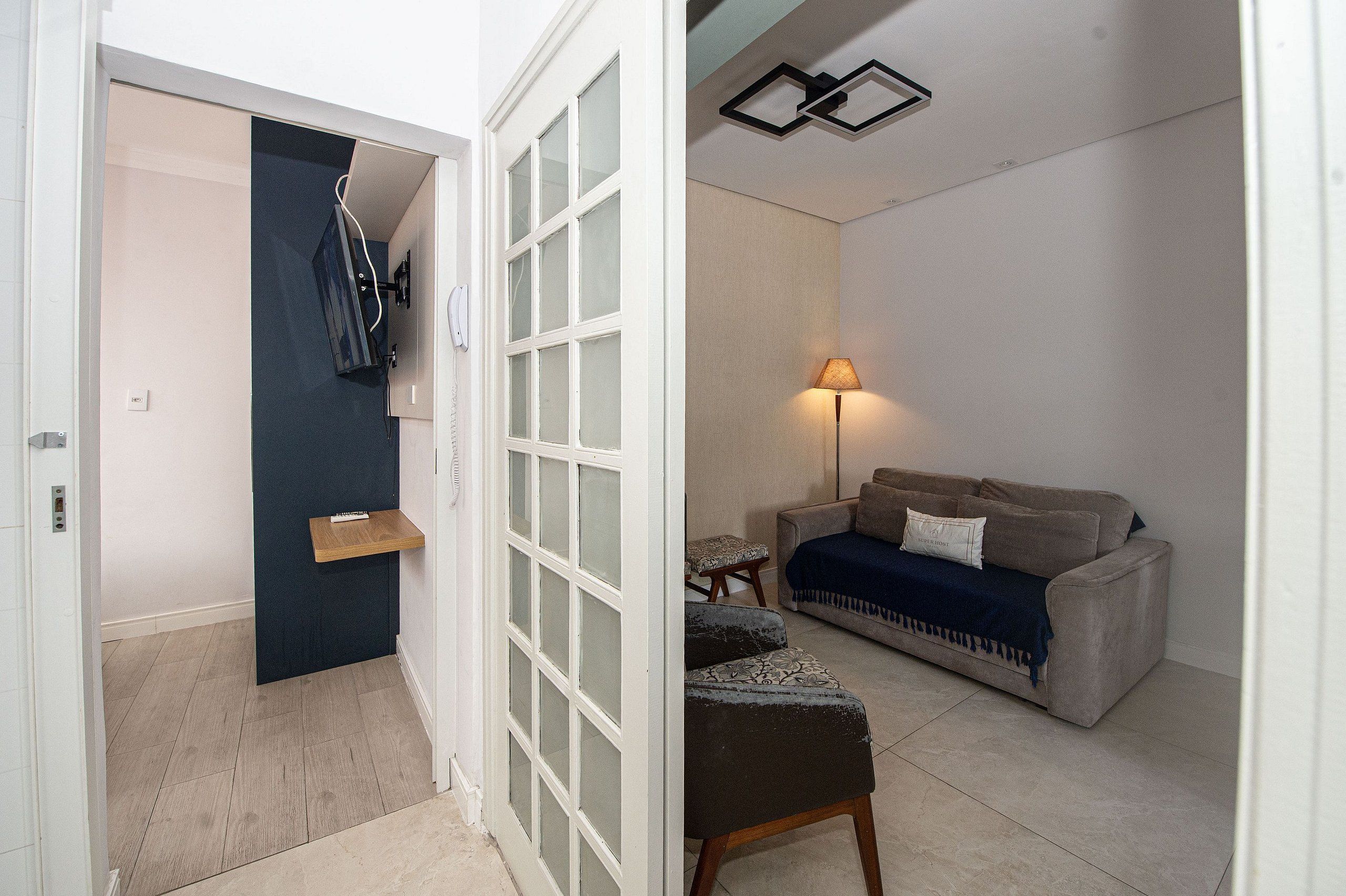 A room with a sofa, a lamp, a small table, and a chair.