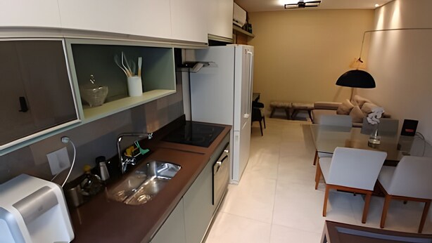 A compact kitchen with a sink, a toaster, and a refrigerator. There is a dining area with a table and chairs.