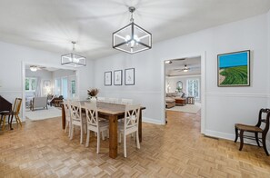 Ein geräumiger Essbereich mit Holztisch und -stühlen, einem Deckenventilator und Wandbildern.