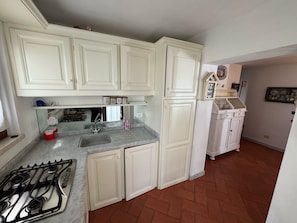 Eine Küche mit weißen Schränken, einem Gasherd, einer Spüle und einem Kühlschrank.