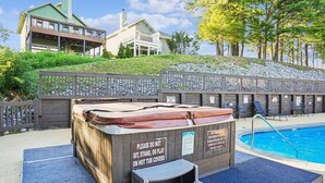 Ein Whirlpool mit Warnschild, ein Schwimmbecken und ein Holzzaun mit Stühlen.