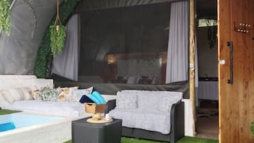 A tent with a sofa, a small table, and a door leading to a room.