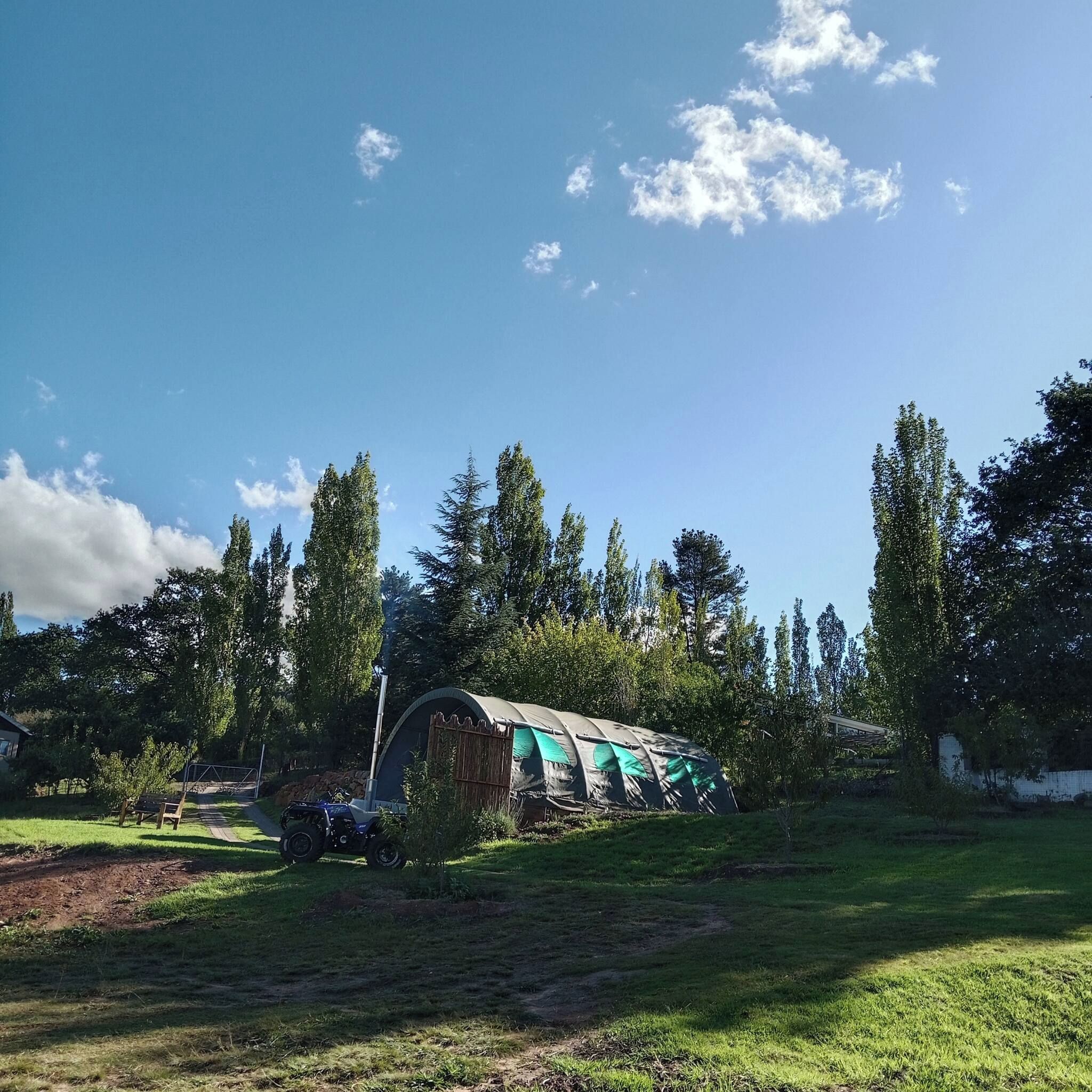 Een tentachtig gebouw in een grasrijke omgeving met bomen op de achtergrond.