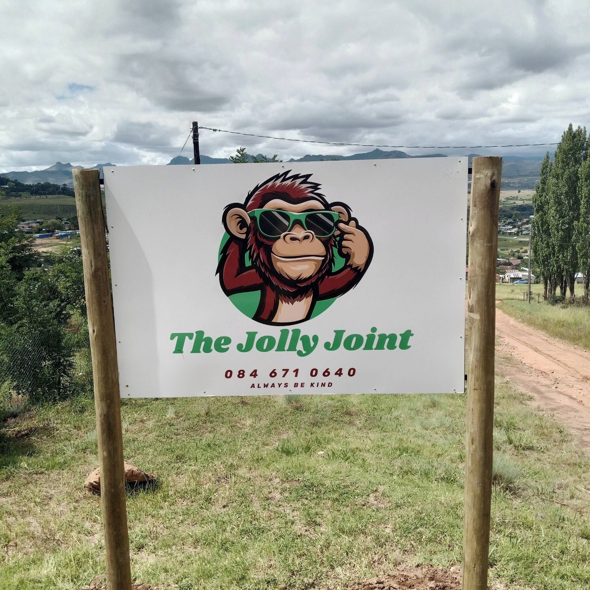 A sign with a cartoon monkey wearing sunglasses and the text 'The Jolly Joint' along with a phone number and a slogan 'ALWAYS BE KIND'.