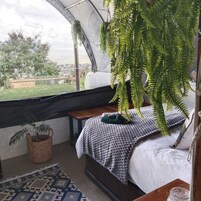 Un dormitorio con cama, una planta colgante, una ventana y vistas al exterior.