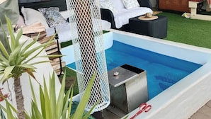 Ett tält med en pool, vita möbler och en hängmatta.