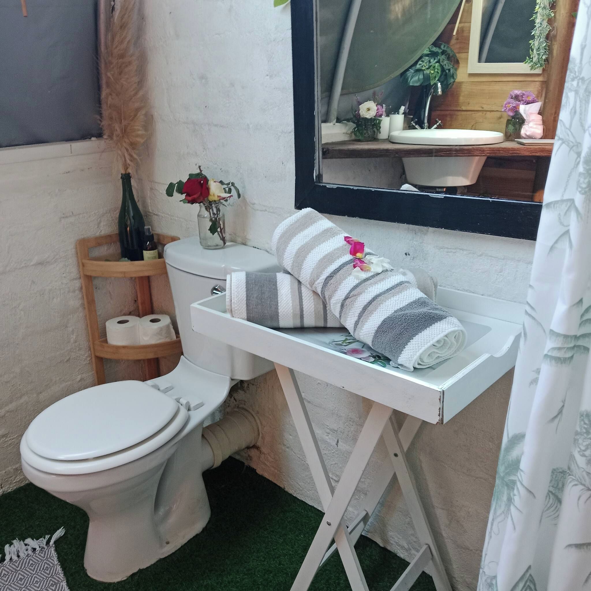 A bathroom with a toilet, a shelf with toiletries, a towel, and a mirror.