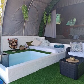 A spa area with a hot tub, a seating area with cushions, and a small table with a decorative item.