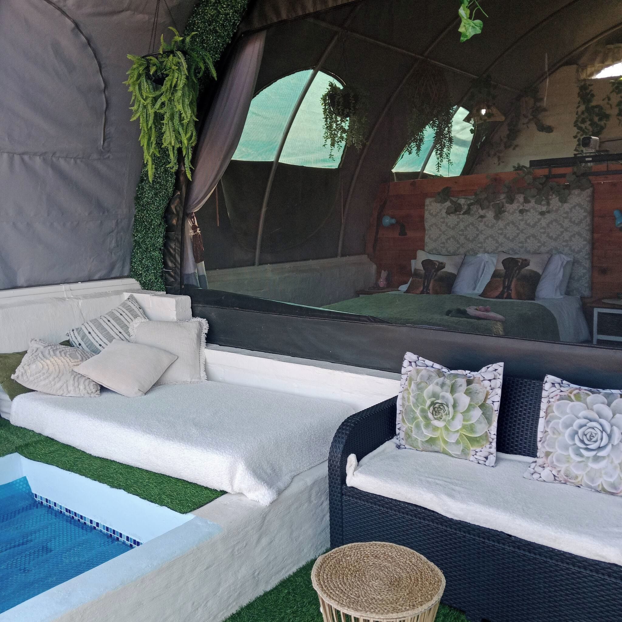 Acomodação em tenda com uma cama, um sofá e uma pequena mesa.