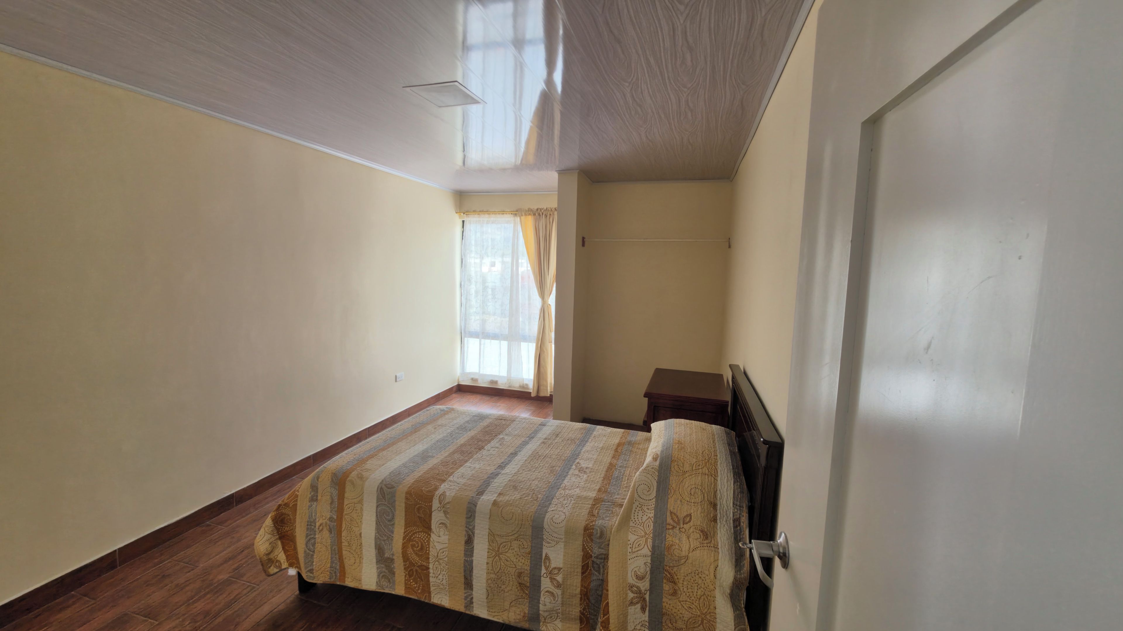 A room with a bed, a door, and a window with curtains.