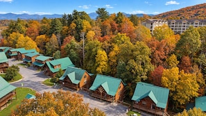 Eine Lodge mit mehreren Holzhäuschen, einer zentralen Zufahrtsstraße und einem Hintergrund aus herbstlich gefärbten Bäumen.