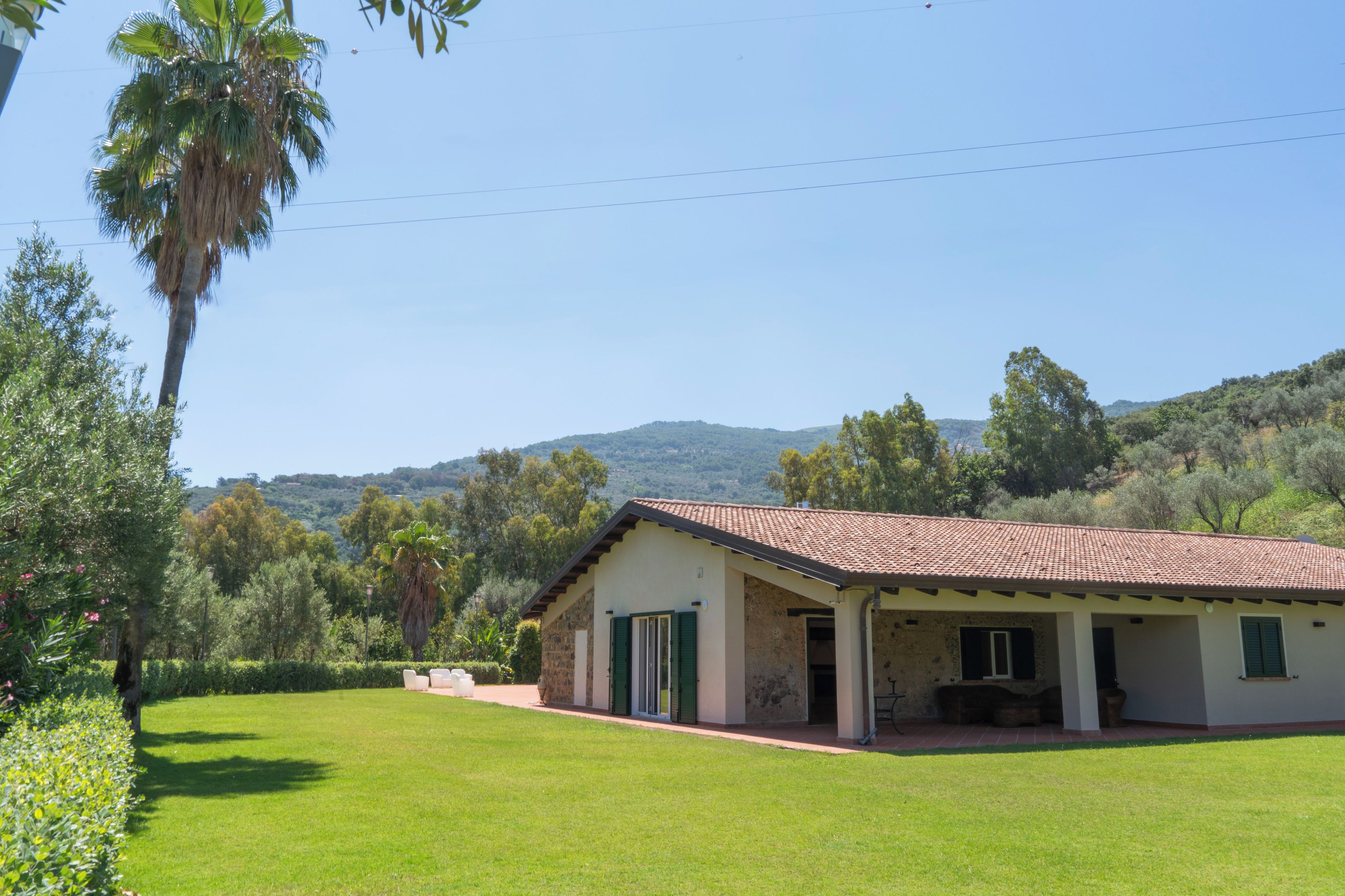 A single-story building with a tiled roof, a stone foundation, and a flat roof extension.