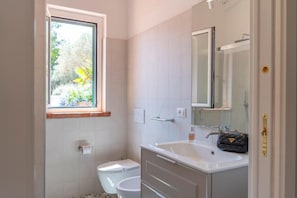 Un baño con inodoro, lavamanos y ventana.