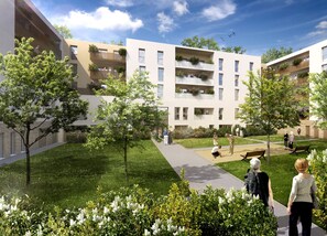 A modern residential building with multiple balconies, a central courtyard with grass and trees, and a clear sky. - DOMITYS - Les Pierres Dorées (Gleizé)