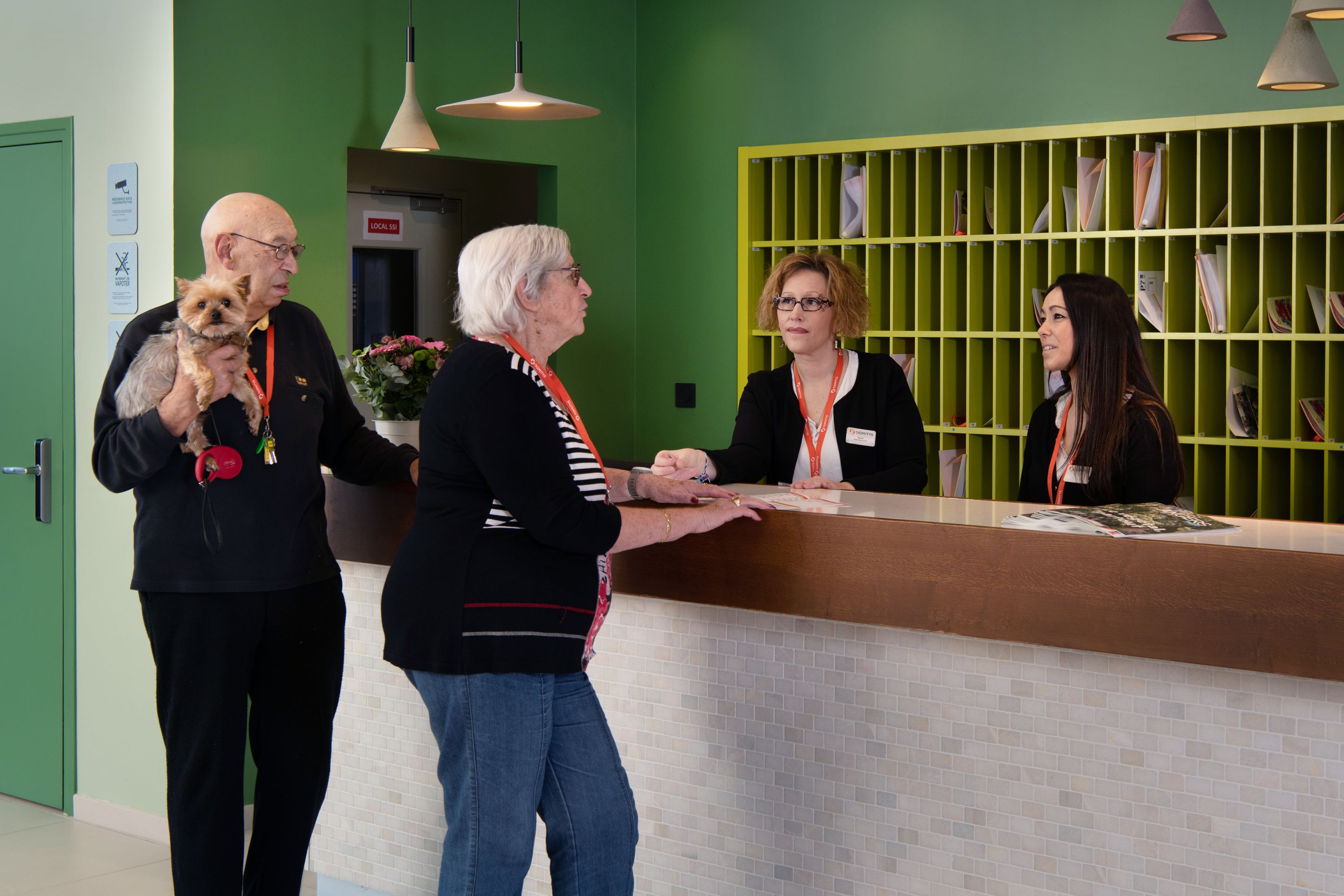 A reception area with a green wall, a reception desk, and a bulletin board with papers.