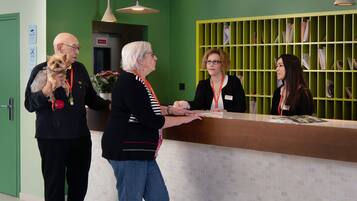 A reception area with a green wall, a reception desk, and a bulletin board with papers.