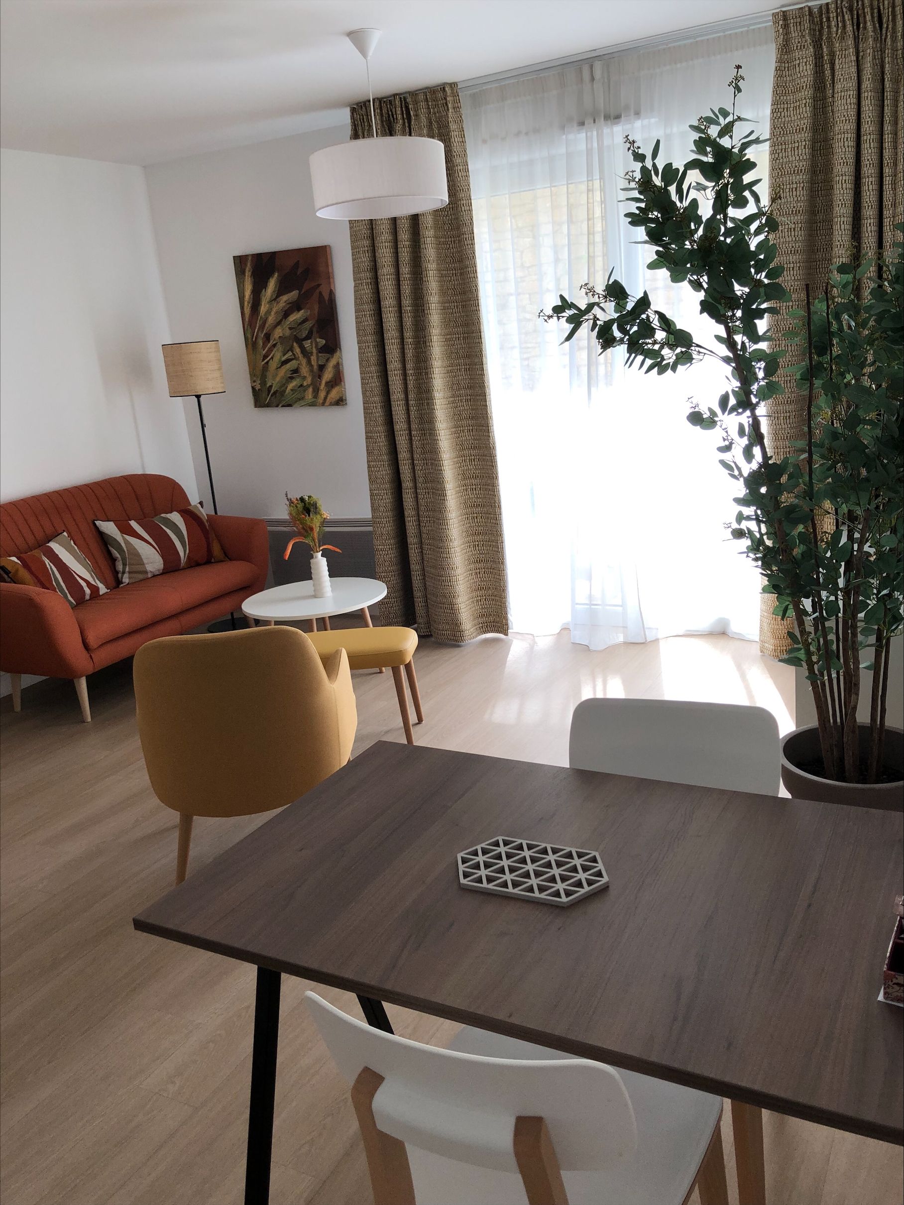 A modern living room with a sofa, a dining table, and a potted plant.