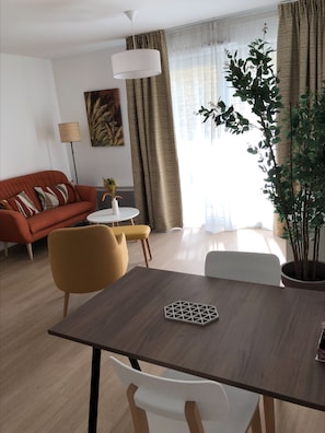 A modern living room with a sofa, a dining table, and a potted plant. - DOMITYS - Les Pierres Dorées (Gleizé)