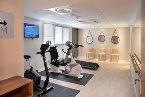 A modern gym with stationary bikes, treadmills, and a television displaying a sports event. - DOMITYS - Les Pierres Dorées (Gleizé)