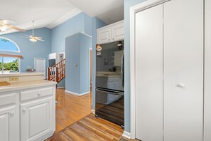 A kitchen with white cabinets, a black refrigerator, wooden flooring, and a ceiling fan. - Colington Harbour 34: Soundfront with Private Dock (Colington)