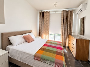 A hotel room with a bed, a dresser, an air conditioning unit, and a window with curtains. - Rokna corner penthouse - 240sqm with sea view in Xaghra Gozo (Ix-Xagħra)
