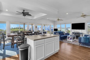 A spacious living area with a large island, a dining table, and a seating area with a blue sofa. - Shining Sea at North Topsail Beach, Steps to the Beach, Dog Friendly (North Topsail Beach)