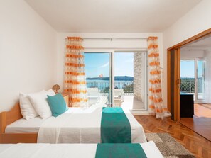 A bedroom with a bed, a nightstand, and a view of a balcony with a railing. - Villa in Seget Donji With Swimming Pool (Seget)