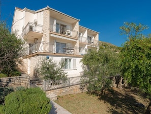 A multi-story residential building with balconies, surrounded by greenery and a clear sky. - Villa in Seget Donji With Swimming Pool (Seget)