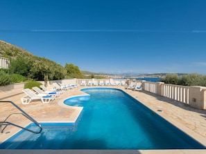 A swimming pool with lounge chairs and a view of the sea. - Villa in Seget Donji With Swimming Pool (Seget)