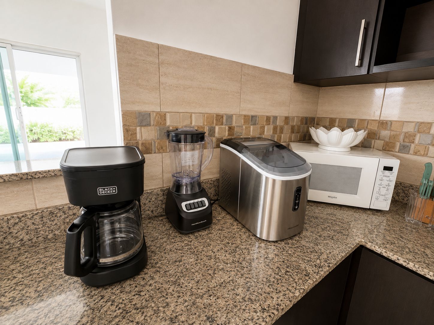 A kitchen with a coffee maker, a blender, and a microwave.