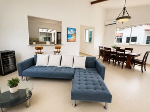 A modern living room with a sectional sofa, a glass coffee table, and a dining area with wooden furniture. - Very spacious house near the beaches in Nueva Gorgona, Malibu Beach, and Casa Kai (Nueva Gorgona,residencial malibu)
