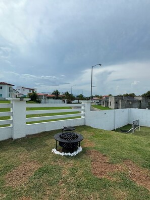 A fenced outdoor area with a barbecue grill, a white fence, and a grassy lawn. - Very spacious house near the beaches in Nueva Gorgona, Malibu Beach, and Casa Kai (Nueva Gorgona,residencial malibu)