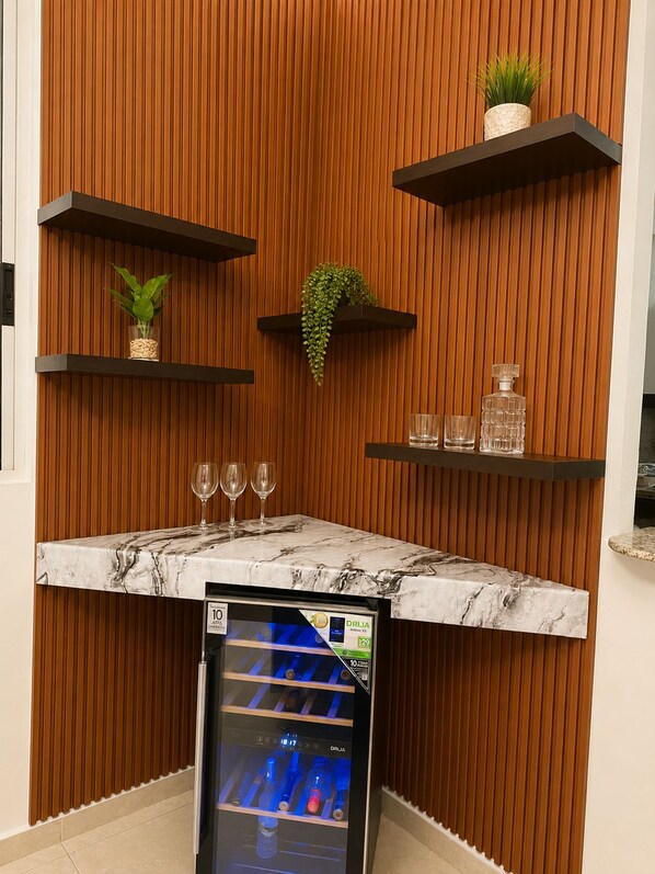 A bar area with a marble countertop, a minibar, and wooden paneling.