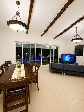 A modern living room with a dining area, a television, and a hammock.