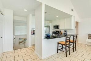 A kitchen with white cabinets, a black countertop, and a built-in microwave. - NEW | Waterfront Getaway | Pet-friendly | Just a 2-minute walk to the beach (Galveston)